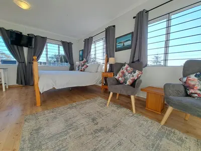 a bedroom with a bed and two chairs at Whale Tale near Kite Beach in Cape Town