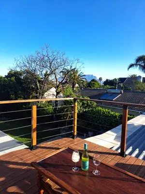 a wooden table with two wine glasses on a deck at Whale Tale near Kite Beach in Cape Town