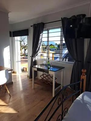 a bedroom with a table in front of a window at Whale Tale near Kite Beach in Cape Town