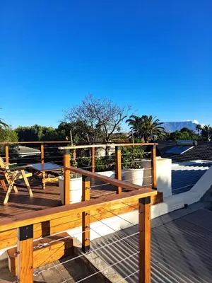 a wooden bench sitting on top of a deck at Whale Tale near Kite Beach in Cape Town