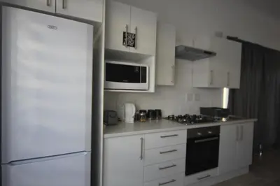 a kitchen with white cabinets and a white refrigerator at The Lily House Hermanus in Hermanus