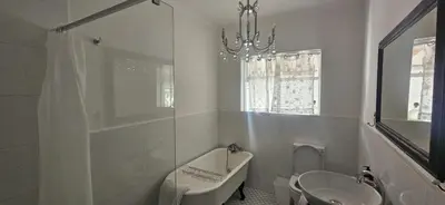 a bathroom with a sink and a bath tub and a toilet at The Lily House Hermanus in Hermanus