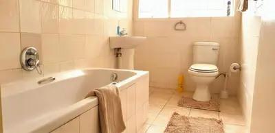 a bathroom with a tub and a toilet and a sink at Riverside Villa in Gordonʼs Bay
