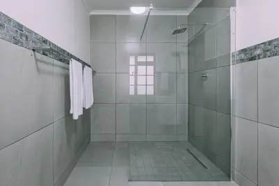 a bathroom with a shower with a glass door at Cornerstone Guesthouse Alk Van Zyl in Panorama
