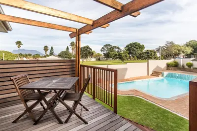 a wooden deck with a table and chairs next to a swimming pool at Cornerstone Guesthouse Alk Van Zyl in Panorama