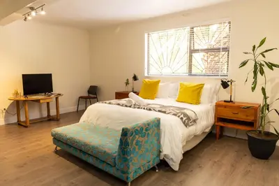 a bedroom with a bed and a chair and a window at Staymore in Stellenbosch