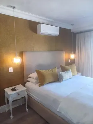 a bedroom with a white bed and a night stand at Thyme Wellness Spa and Guesthouse in Cape Town