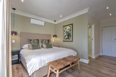 a bedroom with a large white bed and a bench at Thyme Wellness Spa and Guesthouse in Cape Town