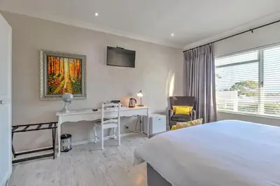 a bedroom with a bed and a desk and a monitor at Thyme Wellness Spa and Guesthouse in Cape Town