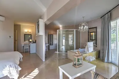 a bedroom with a bed and a living room at Thyme Wellness Spa and Guesthouse in Cape Town