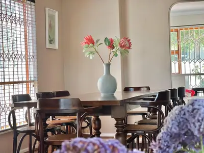 a table with a vase of flowers on top of it at Princess Holiday Home in Cape Town