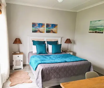 a bedroom with a large bed with blue pillows at Silverdunes - Seaview in Bettyʼs Bay