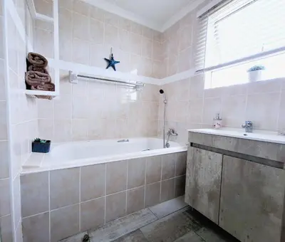 a bathroom with a bath tub and a sink at Silverdunes - Seaview in Bettyʼs Bay