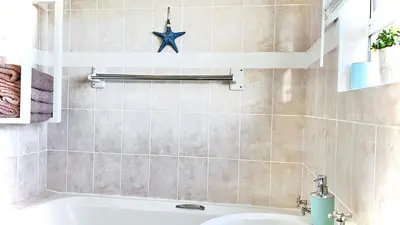a bathroom with a sink and a bath tub at Silverdunes - Seaview in Bettyʼs Bay