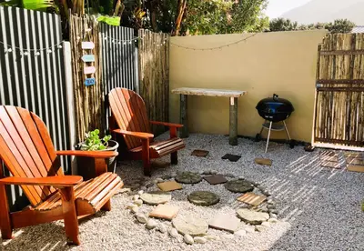 a patio with two chairs and a table and a grill at Silverdunes - Seaview in Bettyʼs Bay