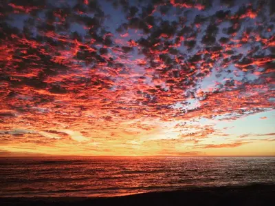 a sunset over the ocean with a cloudy sky at Flavours at 34 in Gordonʼs Bay