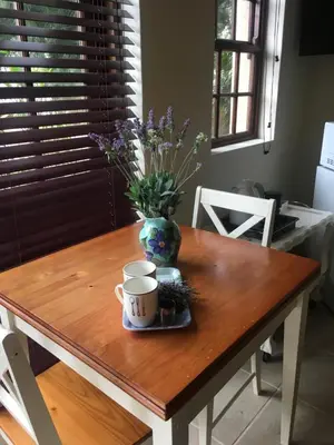 a table with a vase of flowers and a cup on it at Flavours at 34 in Gordonʼs Bay