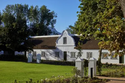 a white house with a thatched roof at Blaauwklippen Manor by NEWMARK in Stellenbosch