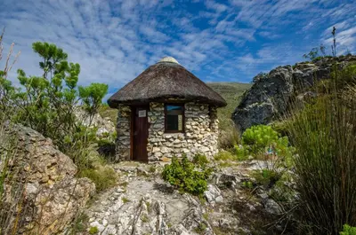 a small stone building with a grass roof on a hill at The Volmoed Trust in Hermanus