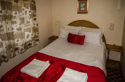 a bedroom with a large bed with white sheets and red pillows at The Volmoed Trust in Hermanus