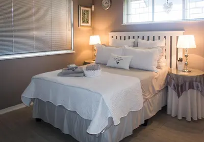 a bedroom with a large bed with white sheets and pillows at The Vintage Crane Guest House in Caledon