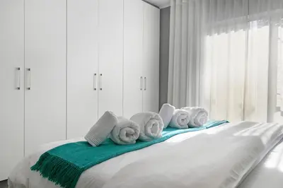 a pile of towels sitting on top of a bed at Century City Luxury Two Bedroom Apartment in Cape Town