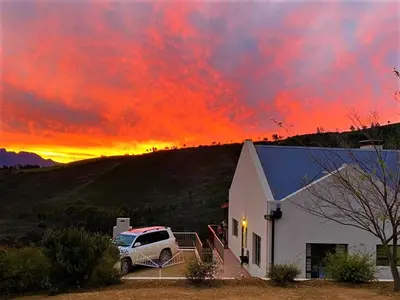 a truck parked in front of a house with a sunset at Vredehoek Guest Farm in Breerivier