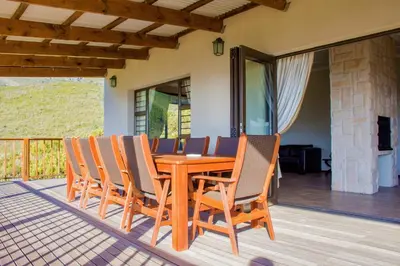 a wooden dining table and chairs on a deck at Vredehoek Guest Farm in Breerivier