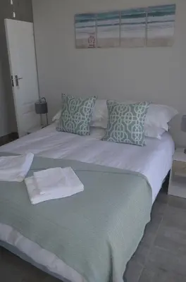 a bed with a green and white blanket and pillows at 808 St Tropez in Cape Town