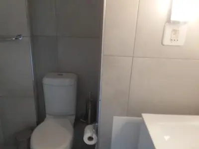 a bathroom with a white toilet and a sink at Sunset 786 Holidays 211 in Strand