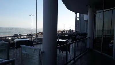 a balcony with tables and chairs and the ocean at Sunset 786 Holiday Accom-212 in Strand