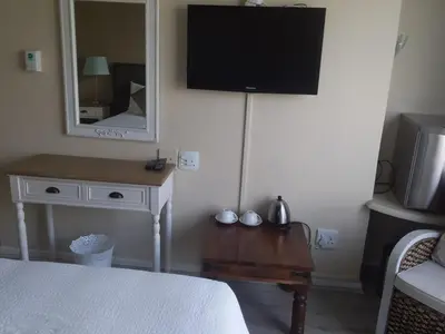 a bedroom with a bed and a tv and a table at Sunset 786 Holiday Accom-212 in Strand