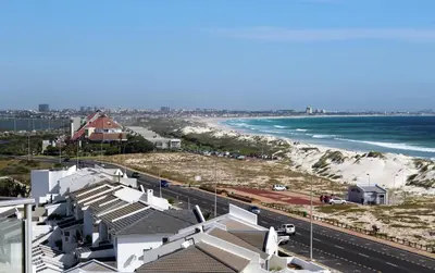 a view of a beach with white buildings and the ocean at 603 Nautica in Cape Town