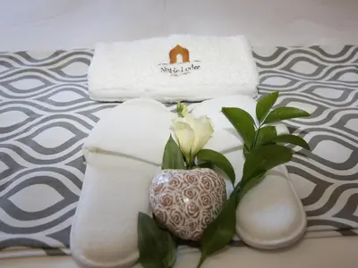 a white flower in a vase next to towels at The Noble Lodge in Cape Town