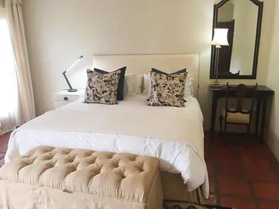 a bedroom with a large white bed with a couch at Navarre Farm Cottages in Stellenbosch