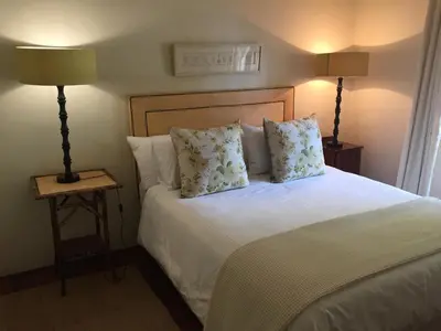a bedroom with a white bed with pillows and two lamps at Navarre Farm Cottages in Stellenbosch