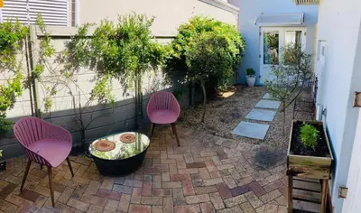 a patio with two pink chairs and a table at Modern studio apartment in Cape Town