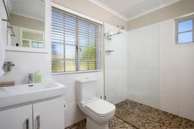 a white bathroom with a toilet and a sink at Quainton Cottages in Hermanus