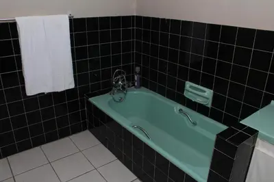 a bathroom with a green tub and black tiles at MO MAJOR in Cape Town