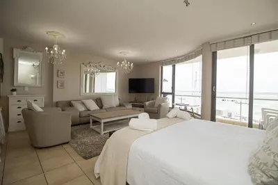 a bedroom with a bed and a living room at Hibernian Towers 402 Self Catering Accommodation Strand Western Cape South Africa in Cape Town