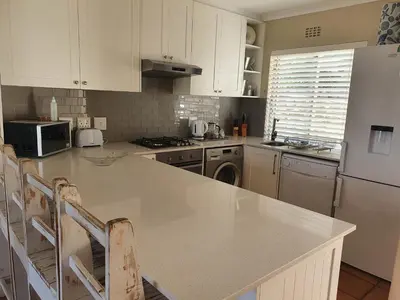a kitchen with white cabinets and a white refrigerator at 57 Whale Rock Estate in Hermanus