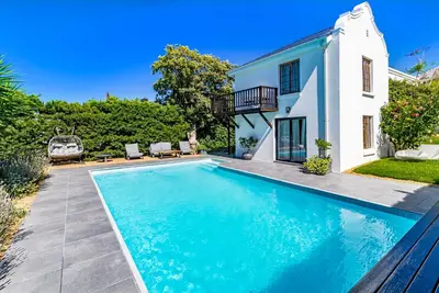 a swimming pool in front of a house at La Bonne Auberge in Somerset West