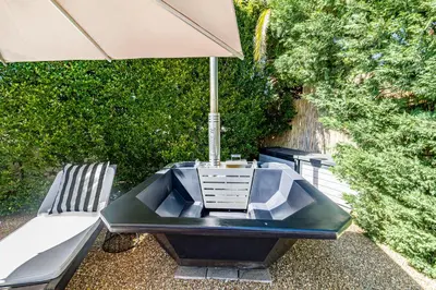 a table with an umbrella next to a chair and a bench at La Bonne Auberge in Somerset West