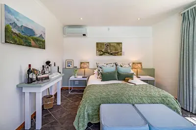 a bedroom with a bed and a desk with two lamps at La Bonne Auberge in Somerset West