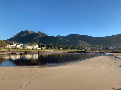 a beach with a bridge and mountains in the background at Bungalow by the sea near Cape Town in Kleinmond