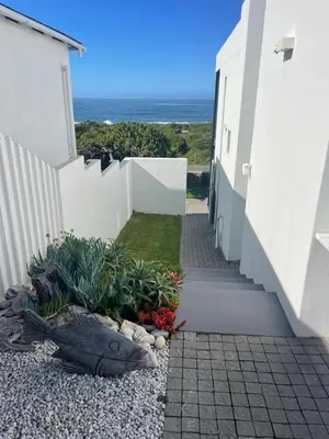 a white house with a white fence and the ocean at Bungalow by the sea near Cape Town in Kleinmond