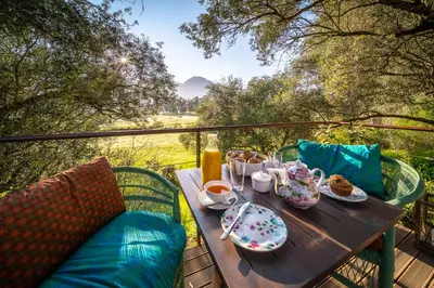 a table with food and drinks on a balcony at Heron House at Bartholomeus Klip in Hermon