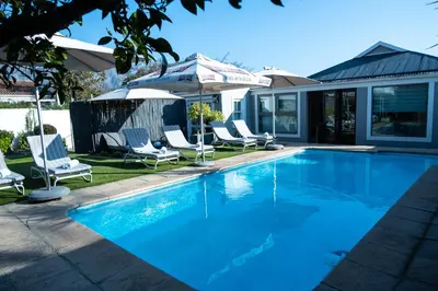 a swimming pool with chairs and umbrellas at LA RÉVERIE in Franschhoek