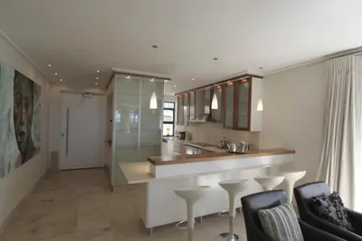 a kitchen with a counter and bar with stools at 74 on Marine in Hermanus