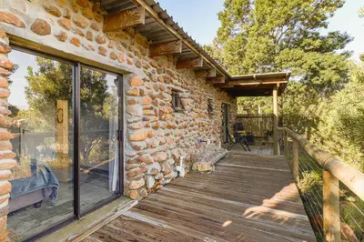 a stone house with a porch and a wooden deck at Steenbok farm cottages Aalwyn Cottage in Wolseley